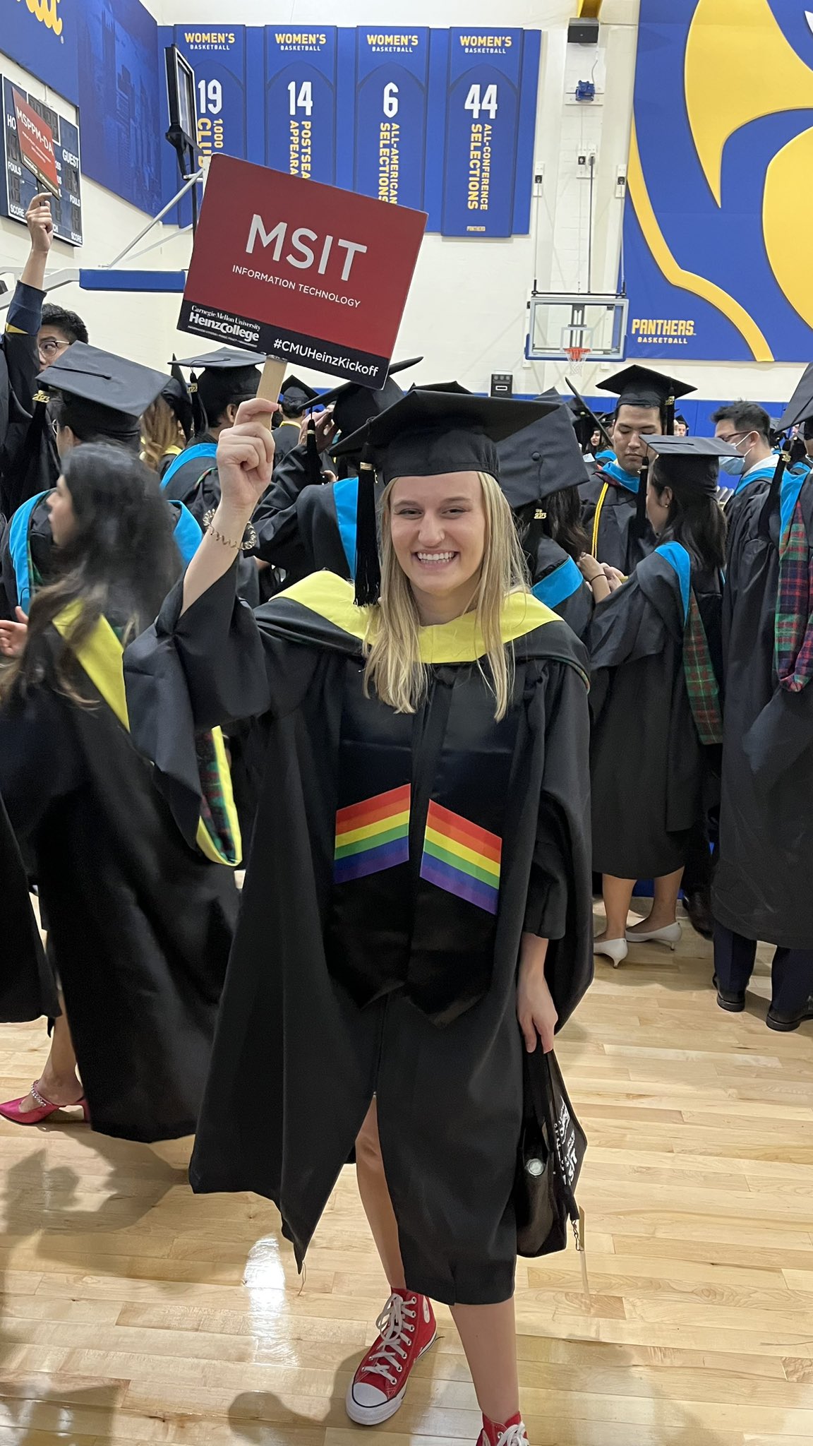 A photo of an MSIT student at Heinz College's graduation ceremony, holding an MSIT sign.