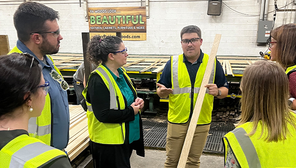 Abby Smith and colleagues wearing yellow vests stand together in a group discussing something.