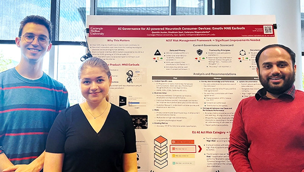 Quentin and two fellow students stand next to their poster presentation.