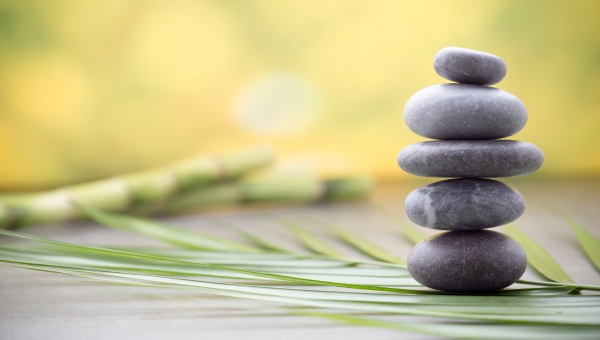 Smooth, stacked round stones sitting on a palm frond